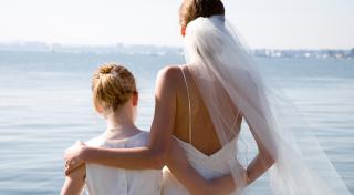 back view of a bride and girl wearing white dresses overlooking a lake