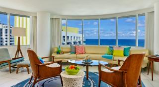 ocean view suite with long fabric couch colourful pillows wooden furniture and a large ocean view windows
